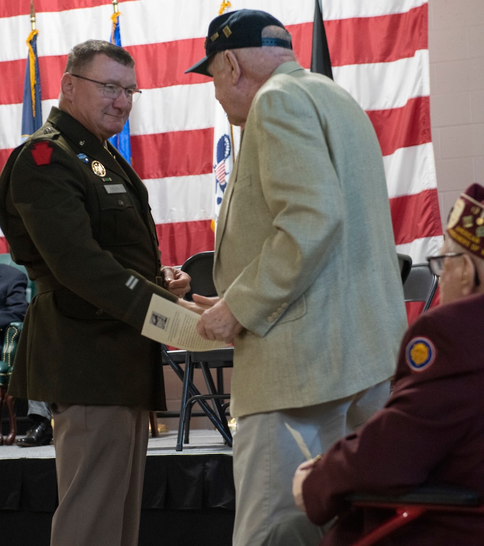 Maj. Gen. Greg Knight, Vermont's adjutant general, presents a coin to Ralph McClintock during the POW/MIA Day observance at Camp Johnson, Vermont, on Sept. 16, 2022. POW/MIA Day is observed the third Friday of September to honor veterans who were held as prisoners of war or who were missing in action. McClintock, one of 83 Sailors aboard the U.S.S. Pueblo when North Korean forces captured the ship, was held hostage by the North Korean army for 11 months.  (U.S. Army National Guard photo by Don Branum)