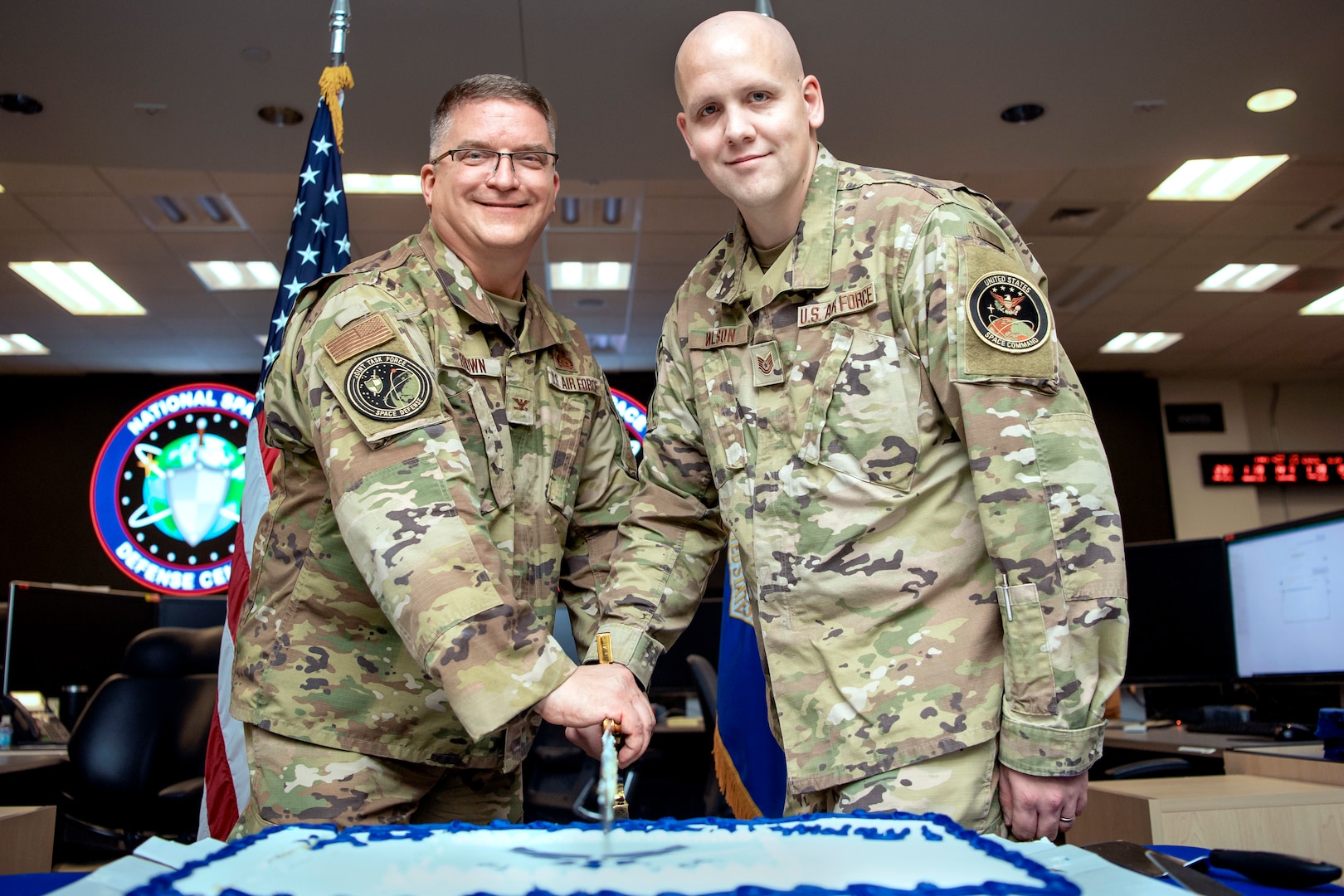 Two men in military uniforms cutting a birthday cake