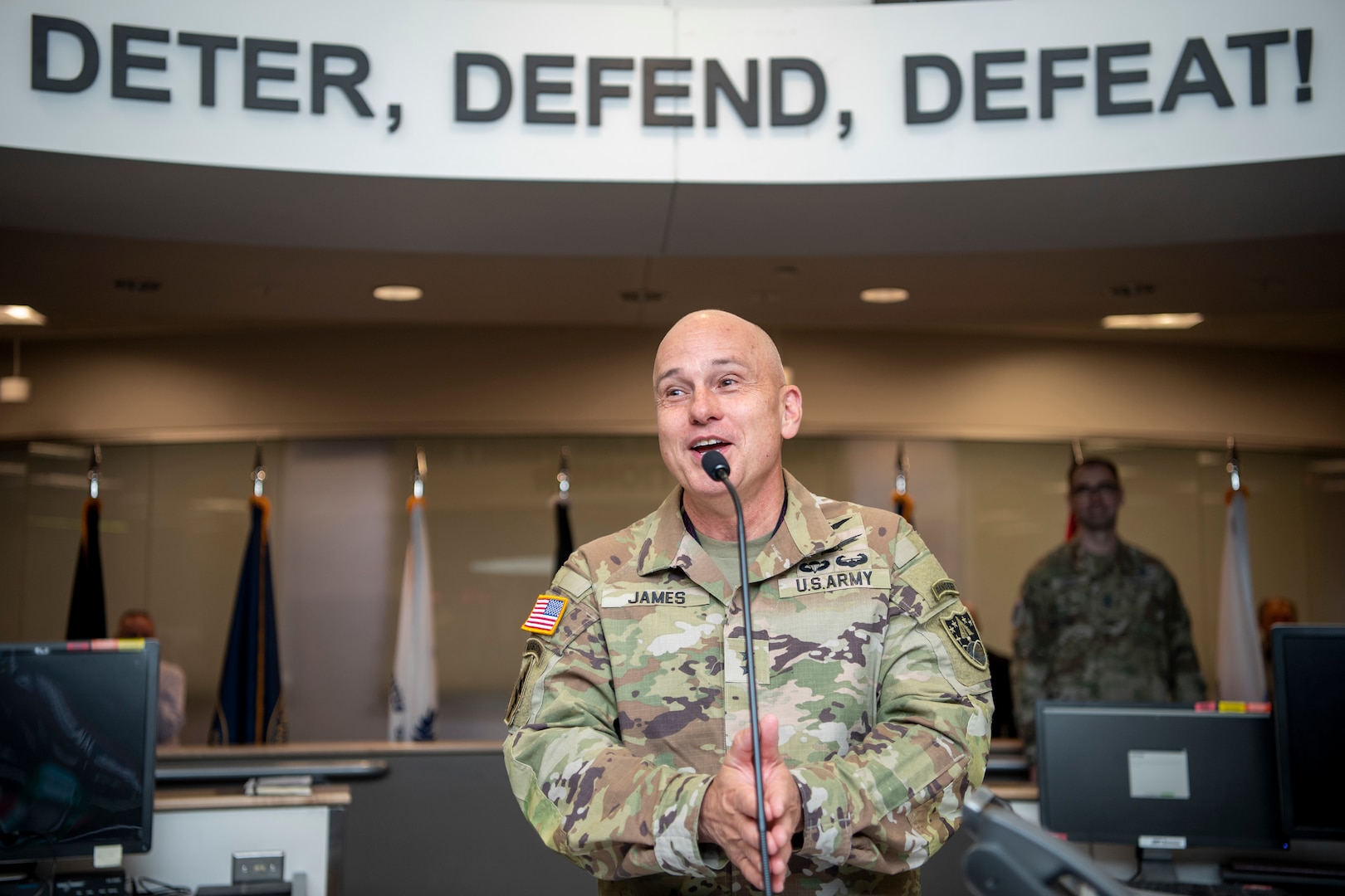Man in military uniform speaks at podium microphone