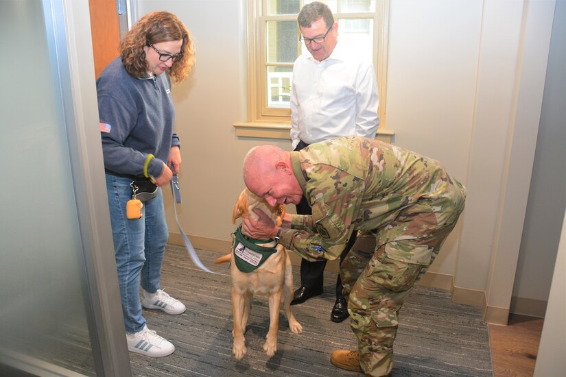 Pennsylvania Adjutant General Maj. Gen. Mark Schindler (right) greets Podrick, the facility dog at the Penn State Student Veteran Center on Sept. 16, 2022, in State College, Pa. Behind them are Renee Thornton-Roop (left), senior director of Penn State's office of veterans programs, and Eugene McFeely, Penn State’s senior director for veteran affairs and services.
