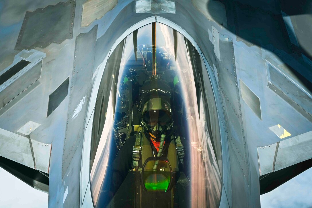 A pilot sits in the cockpit of a plane.