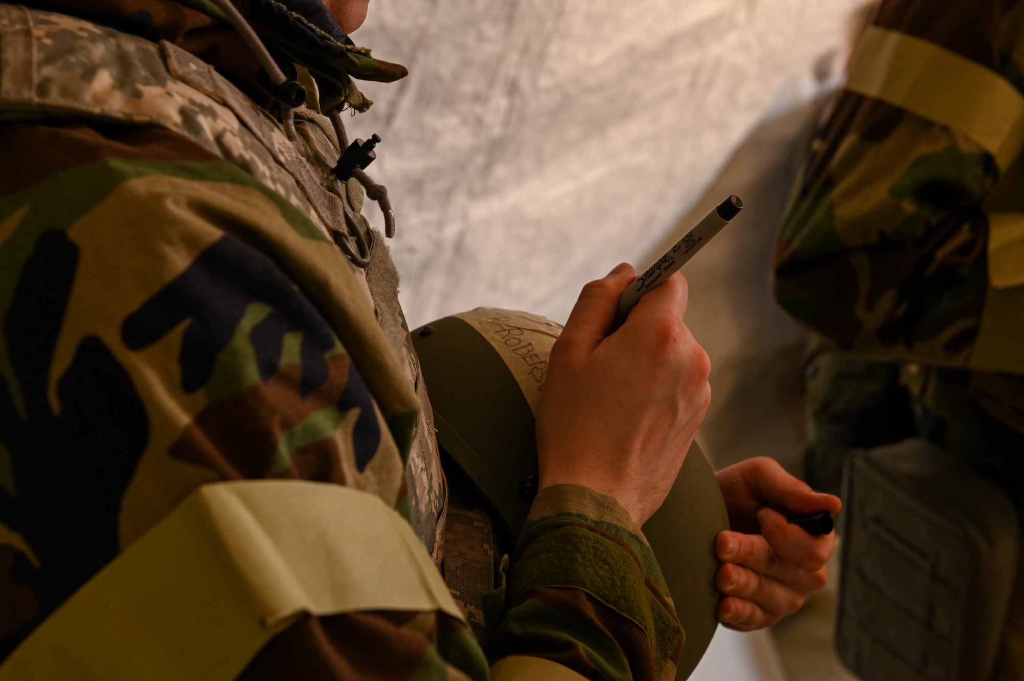 A U.S. Air Force Airmen prints his name across the helmet a part of the gear he wears during the CBRN exercise at Whiteman Air Force Base, Missouri, September 15, 2022. There are five stages of MOPP gear beginning at MOPP 0 and increasing to MOPP 4 depending on the CBRN threat. (U.S. Air Force photo by Airman 1st Class)