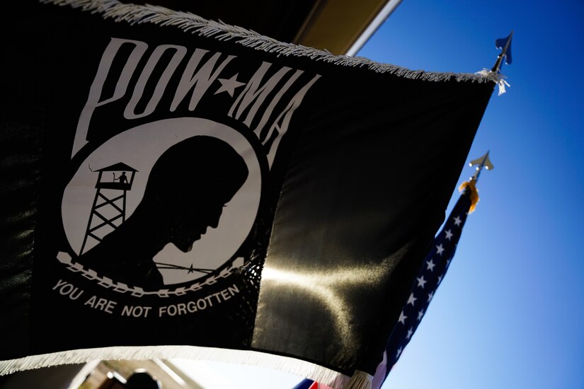 A black flag with a white circle containing a silhouette of a person waves in the wind.