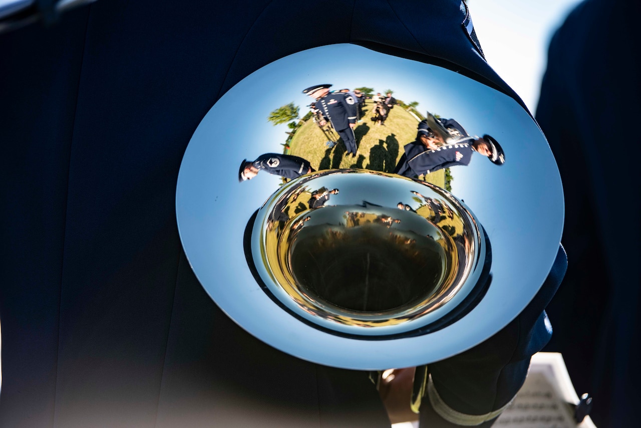 Airmen are reflected on the surface of a horn held by a service member.