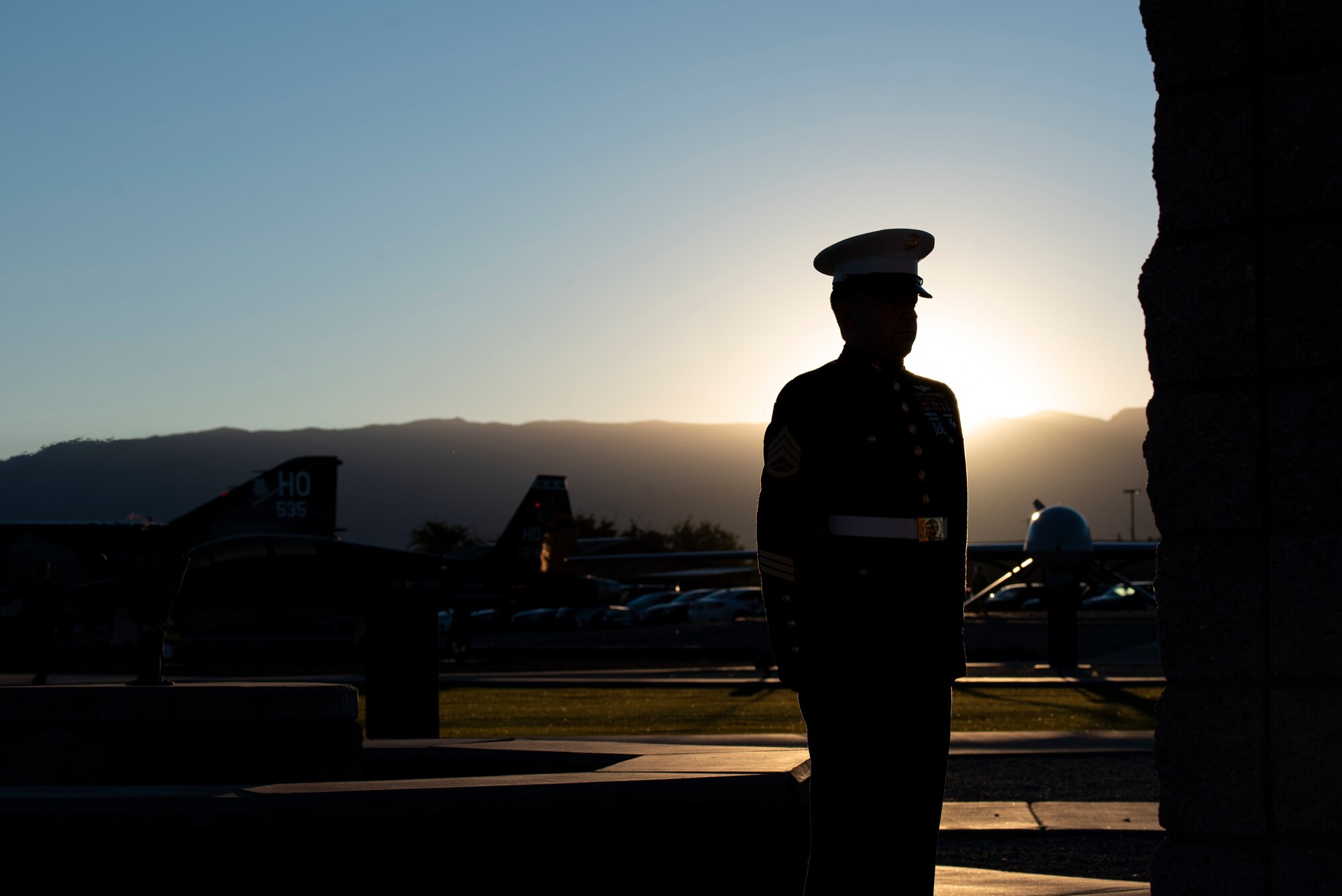 A man in a Marine Corps dress uniform stands in front of the eternal flame.