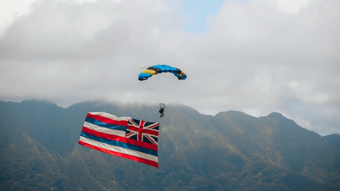 A performer with “The Flying Leathernecks” descends with the Flag of the state of Hawaii at the 2022 Kaneohe Bay Air Show, Marine Corps Air Station Kaneohe Bay, MCBH, Aug. 13, 2022. The air show was hosted in order for the local community, service members and residents of MCBH to interact during a world-class event. The Kaneohe Bay Air Show, which contained aerial performances, static displays, demonstrations and vendors, was designed to express MCBH’s appreciation to the residents of Hawaii and their continued support of the installation. (U.S. Marine Corps photo by Cpl. Patrick King)