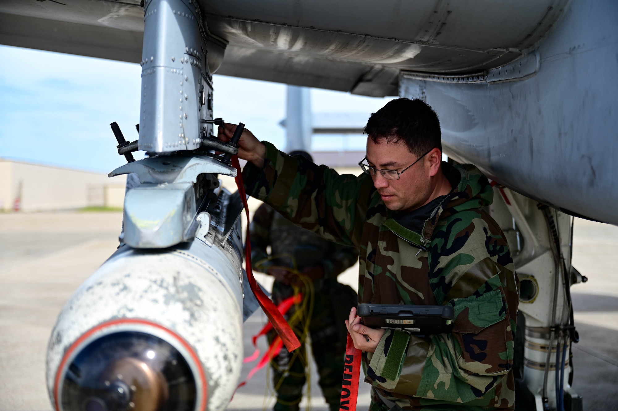 Airman under aircraft attaching red tag.
