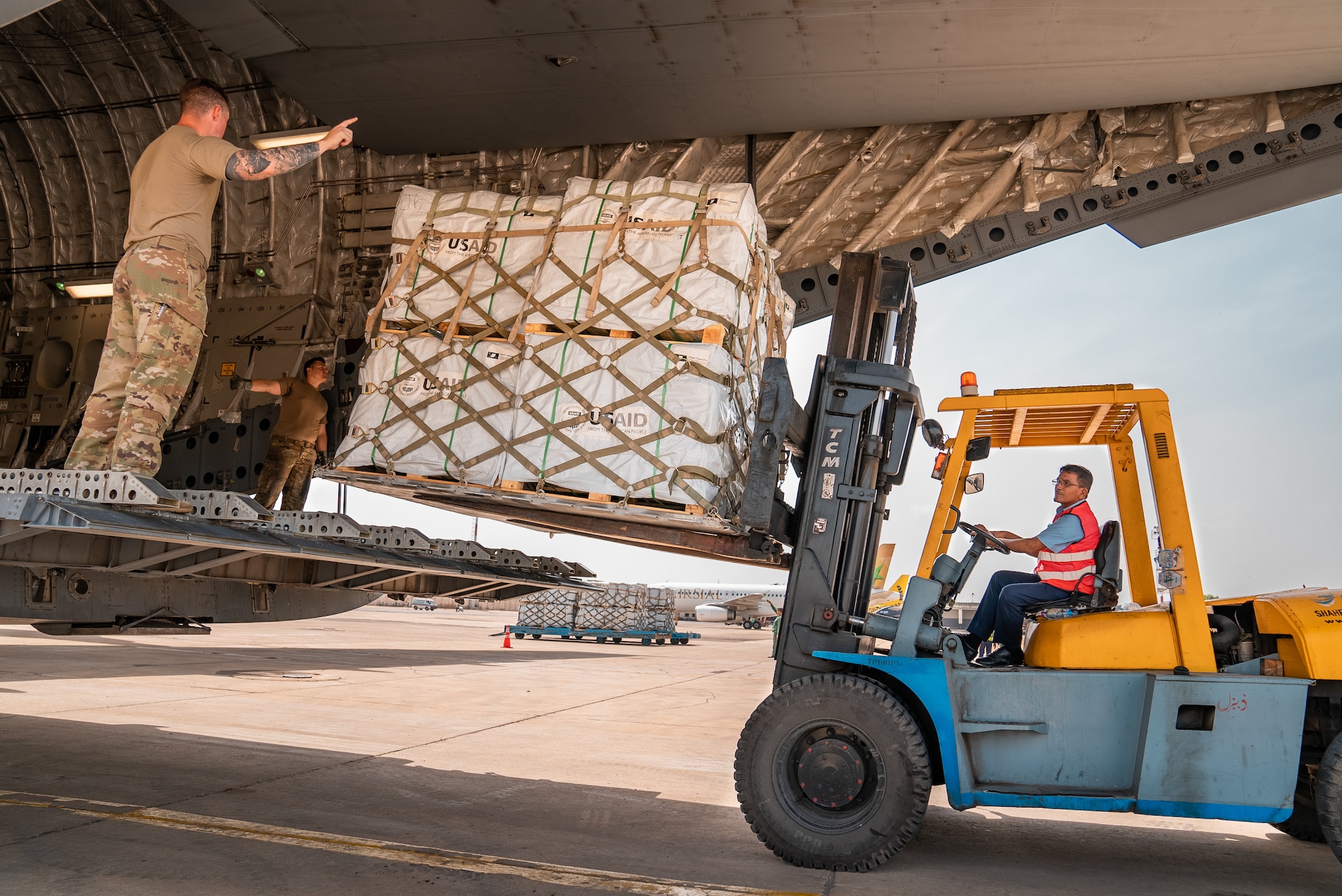 U.S. military personnel assigned to United States Air Forces Central Command work with Karachi Airport members to unload critical supplies at Karachi Airport, Pakistan, in support of a USAID-led humanitarian mission in Pakistan, Sep. 15, 2022. USAID leads the U.S. Government's international development and disaster assistance, helping people emerge from humanitarian crises, such as the catastrophic flooding currently plaguing Pakistan. (Courtesy photo by Narender Kumar)