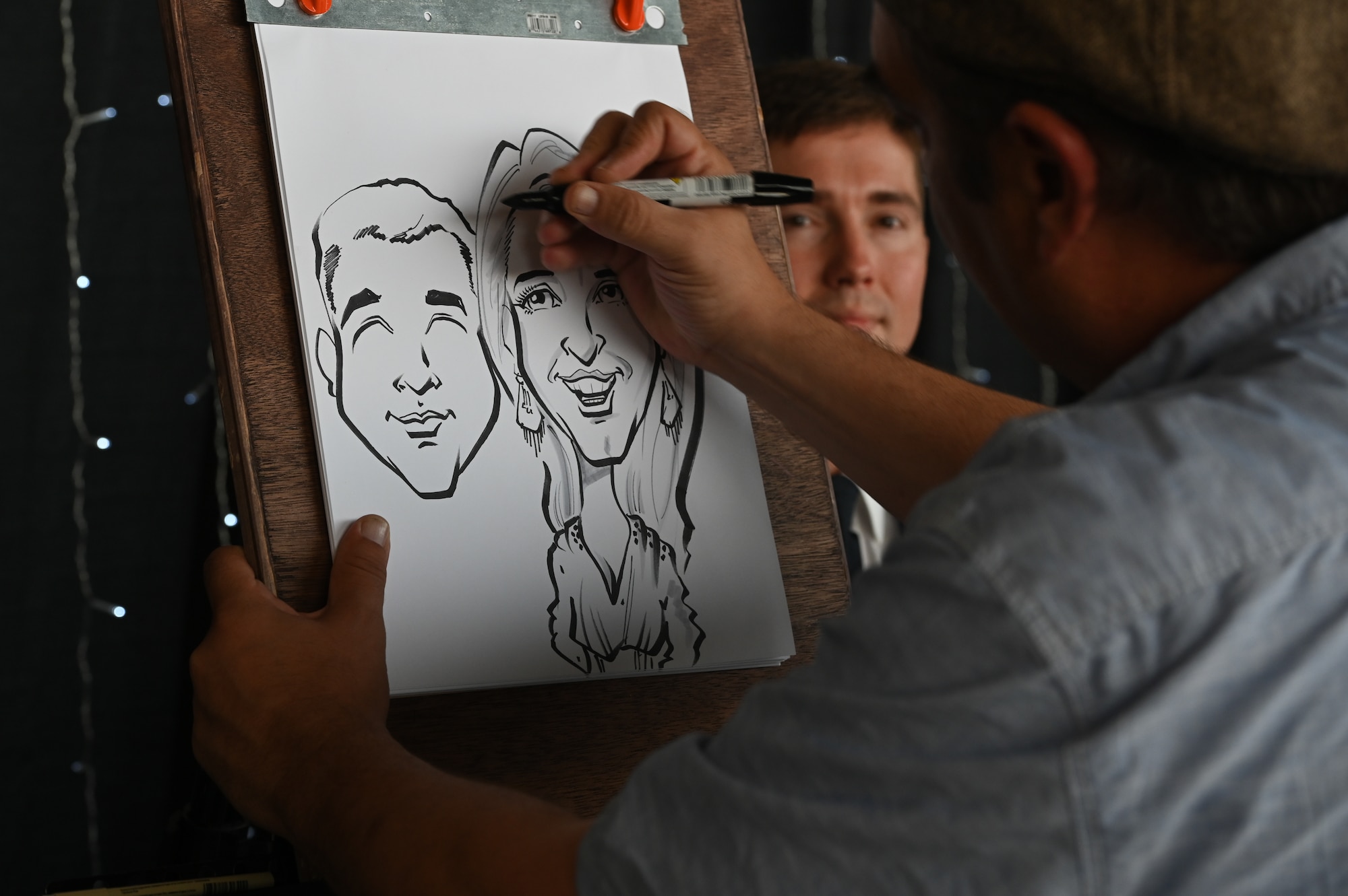 An artist draws a portrait of a couple at the Air Force Ball at Whiteman Air Force Base, Missouri, September 16, 2022. The AF Ball provided services such as drawn portraits and photo booths for Airmen to have souvenirs, remembering the event. (U.S. Air Force photo by Airman 1st Class Joseph Garcia)