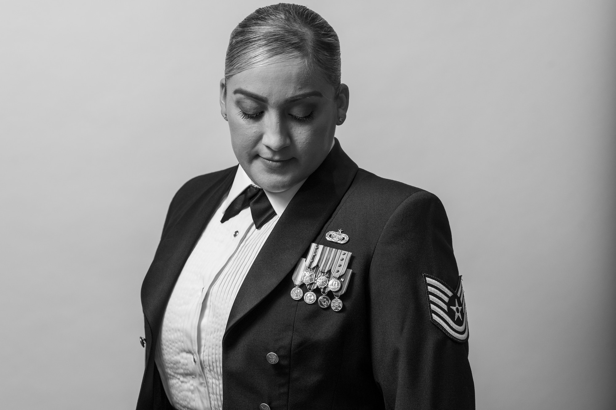 A woman in a ceremonial military uniform stands in front of a white background.