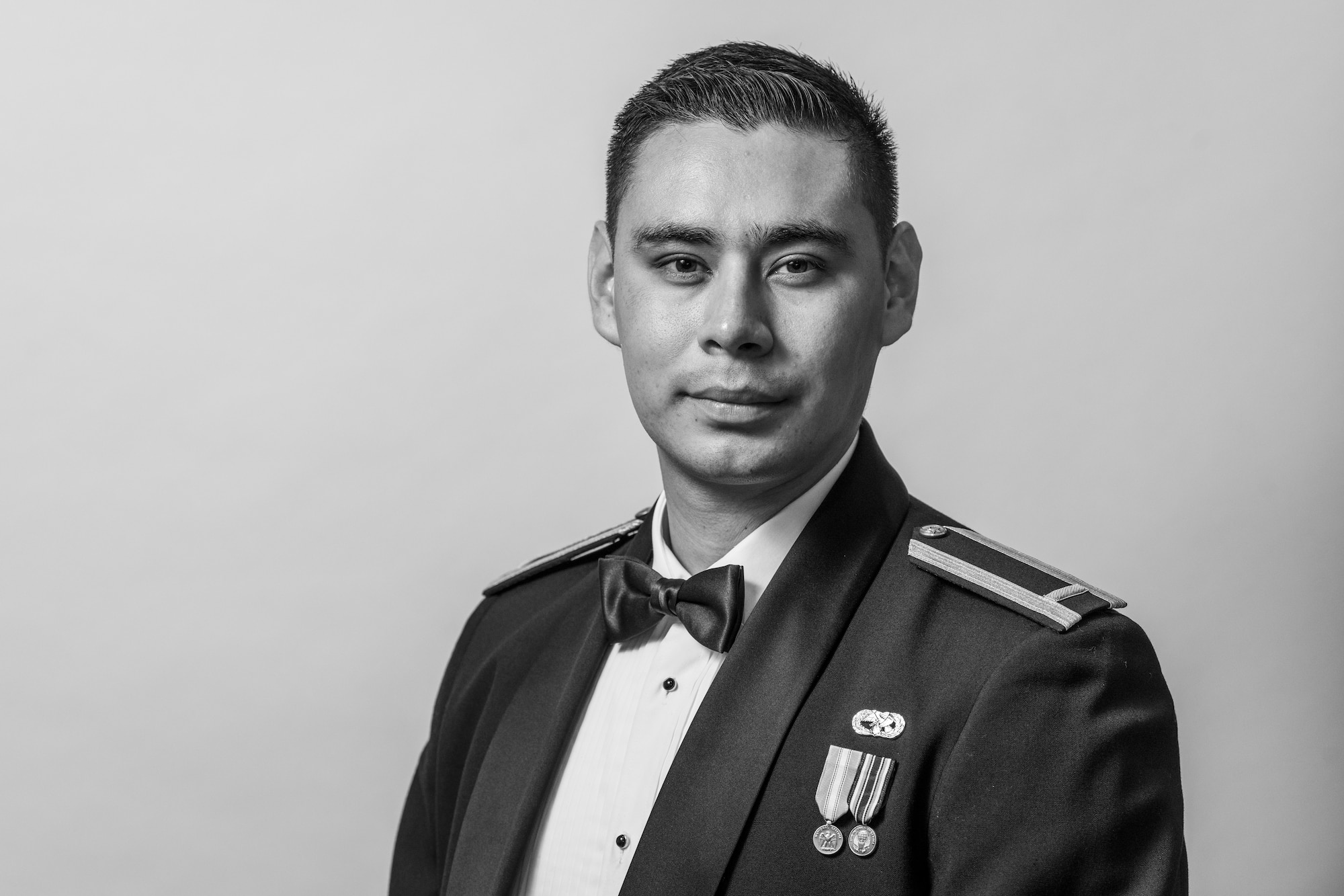 A man in a ceremonial military uniform stands in front of a white background.