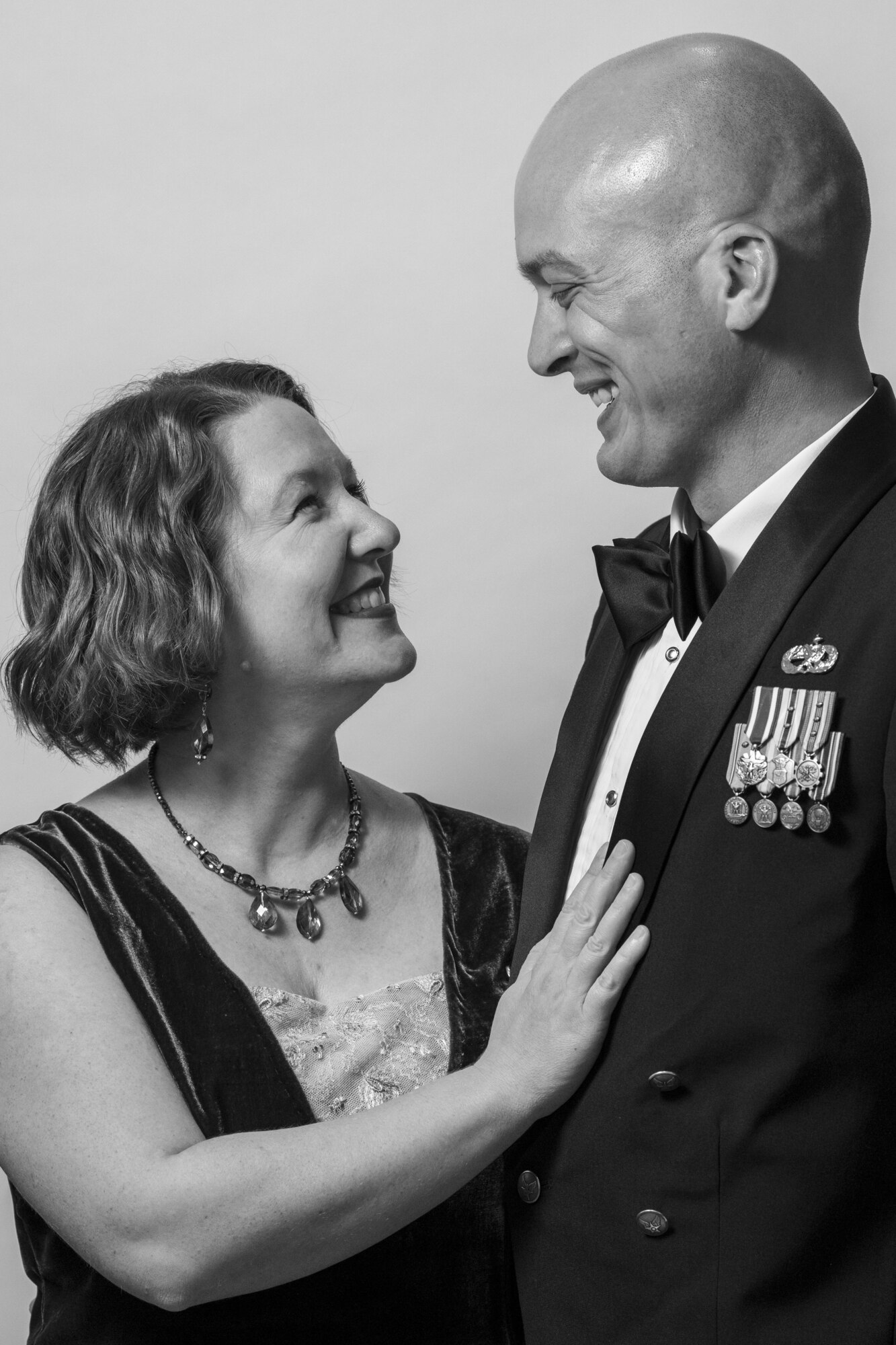 A couple stands in front of a white background with really nice clothes on.