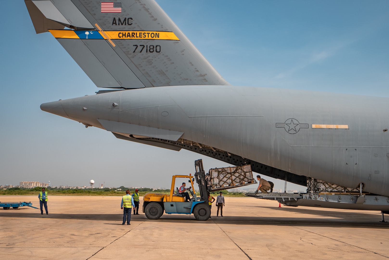 U.S. military personnel assigned to United States Air Forces Central Command work with Karachi Airport members to unload critical supplies at Karachi Airport, Pakistan, in support of a USAID-led humanitarian mission in Pakistan, Sep. 15, 2022. USAID leads the U.S. Government's international development and disaster assistance, helping people emerge from humanitarian crises, such as the catastrophic flooding currently plaguing Pakistan. (Courtesy photo by Narender Kumar)