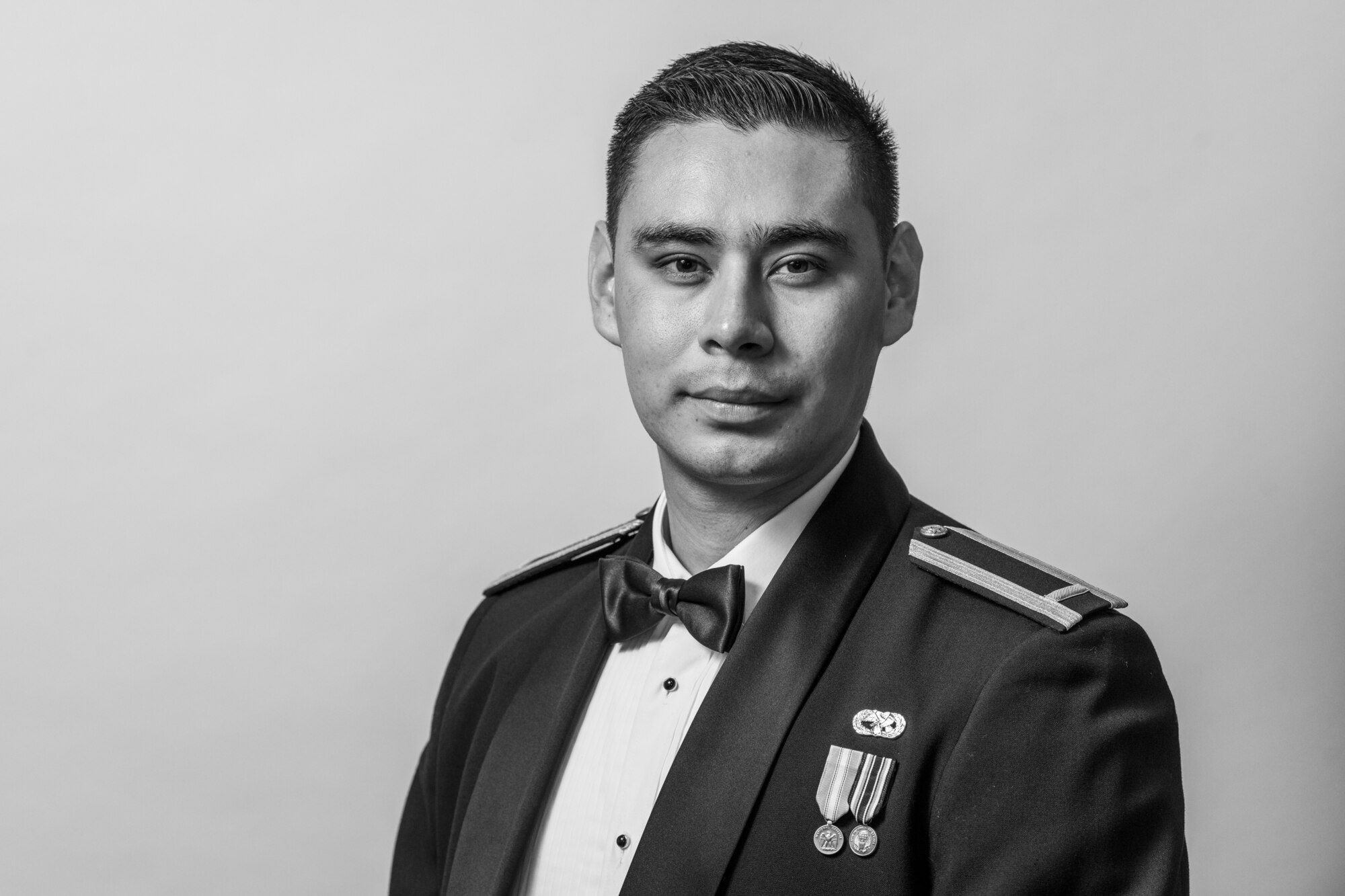 A man in a ceremonial military uniform stands in front of a white background.