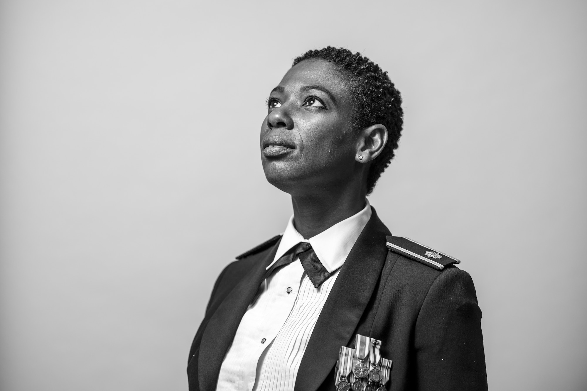 A woman in a ceremonial military uniform stands in front of a white background.