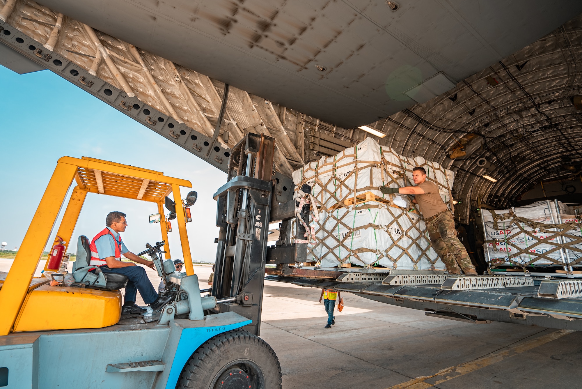 U.S. military personnel assigned to United States Air Forces Central Command work with Karachi Airport members to unload critical supplies at Karachi Airport, Pakistan, in support of a USAID-led humanitarian mission in Pakistan, Sep. 15, 2022. USAID leads the U.S. Government's international development and disaster assistance, helping people emerge from humanitarian crises, such as the catastrophic flooding currently plaguing Pakistan. (Courtesy photo by Narender Kumar)