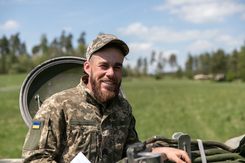 A Ukrainian soldier poses in the hatch of a military vehicle.