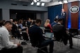 A uniformed service member briefs members of the press.