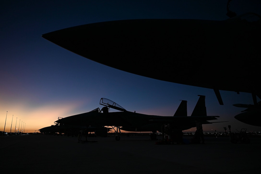 Aircraft are parked at a military base at twilight.
