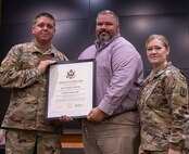 Matthew Dixon (center), spouse of retiring Command Sgt. Maj. Mary Dixon, of Chapin, Illinois, is presented a certificate of appreciation by Lt. Col. Wyatt Bickett, officer-in-charge, 129th Regiment (Regional Training Institute), during a retirement ceremony Sept. 18 at the Illinois Military Academy on Camp Lincoln, Springfield, Illinois.