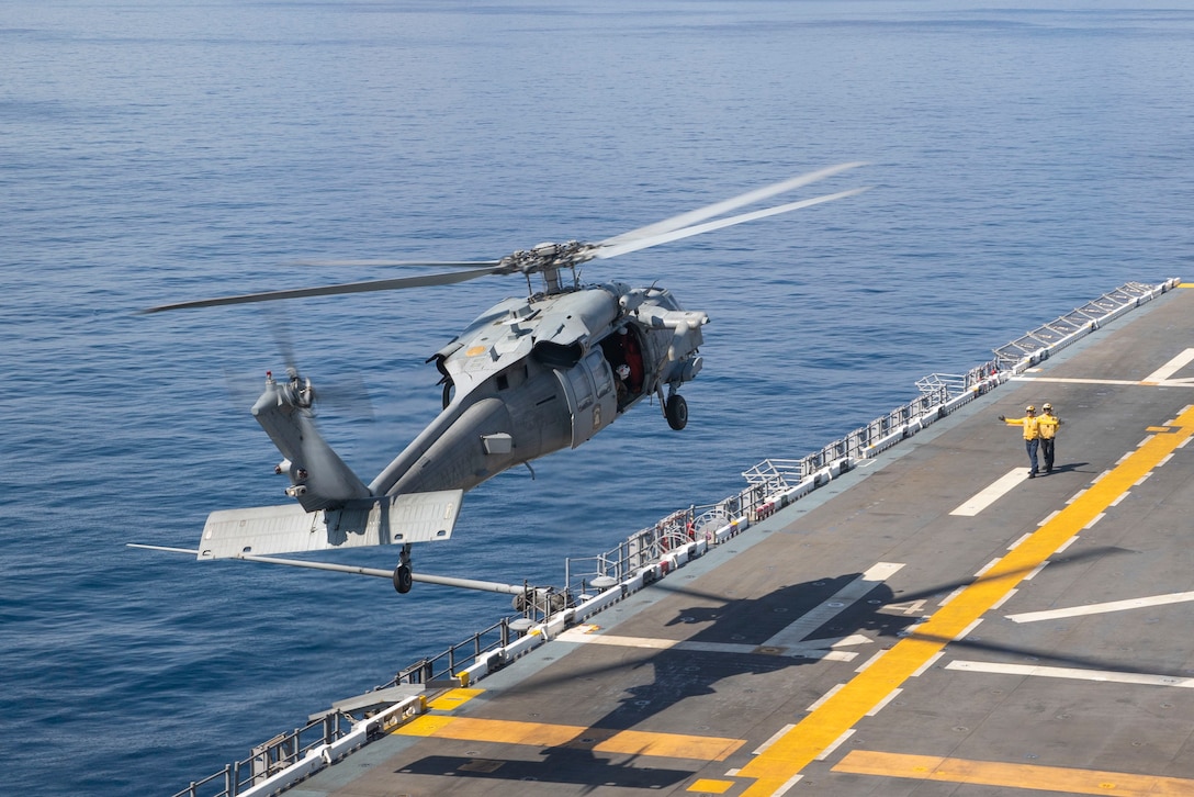 A helicopter takes off from a ship at sea.