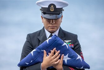 Chief Aviation Electronics Technician Jennifer Warzecha holds an  American flag while performing as the flag bearer during a burial at sea ceremony aboard USS Gerald R. Ford (CVN 78).