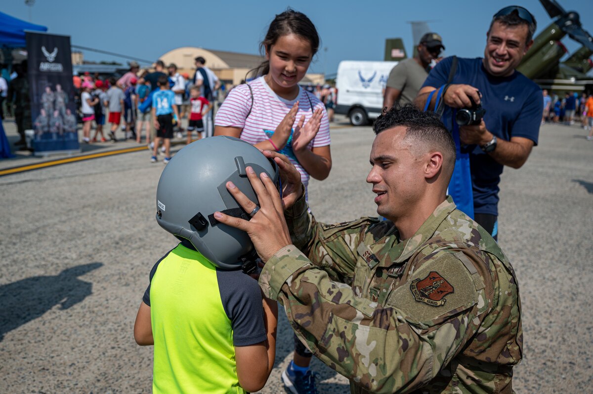 U.S. Air Force Staff Sgt. Daitin Stark, alert crew chief, 113th Wing, District of Columbia Air National Guard, places a fighter pilot’s helmet on a child at the Joint Base Andrews Air & Space Expo at Joint Base Andrews Air Base, Maryland, Sept. 17, 2022. The D.C. Air National Guard celebrated the Air Force’s 75th anniversary Sept. 17-18, 2022, with youth groups, families and veterans in attendance.