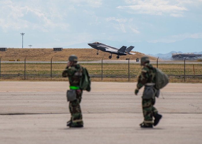 An F-35A Lightning II from the 388th Fighter Wing takes off from Hill Air Force Base, Utah, September 15th, 2022, as Airmen from the 421st Fighter Generation Squadron walk across the flight line during a readiness exercise. The exercise consisted of self-aid buddy care, chemical attacks, and their ability to survive and operate in a simulated deployed scenario. (U.S. Air Force photo by Staff Sgt. Codie Trimble)