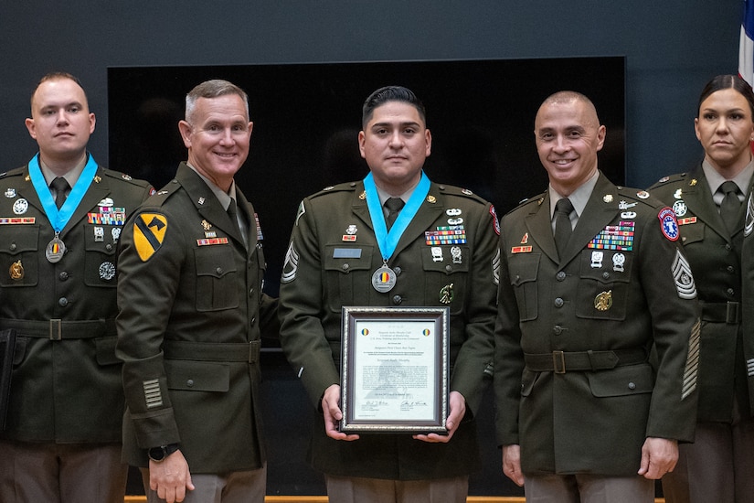 three people wearing U.S. army uniforms posed on a stage accepting awards.