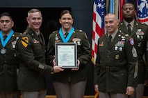 three people wearing U.S. army uniforms posed on a stage accepting awards.