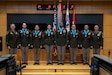 three people wearing U.S. army uniforms posed on a stage accepting awards.