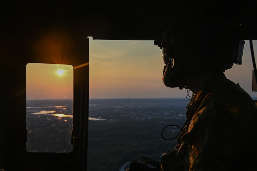 Tech. Sgt. Zachary From, 1st Helicopter Squadron flight engineer, looks at the sunset from inside of an UH-1N Huey before a flyover at Audi Field, Washington D.C., Sept. 16, 2022.