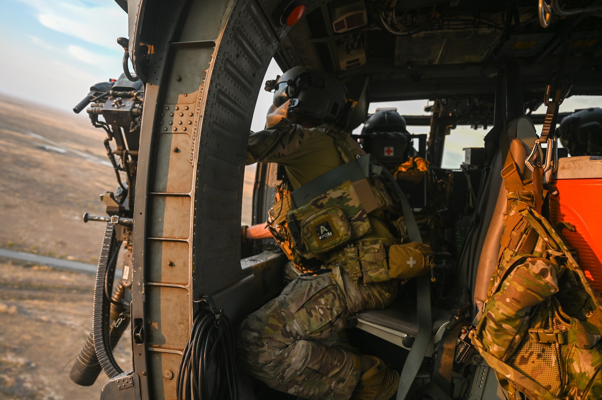 A photo of an Airman firing an HH-60G Pavehawk's mini-gun