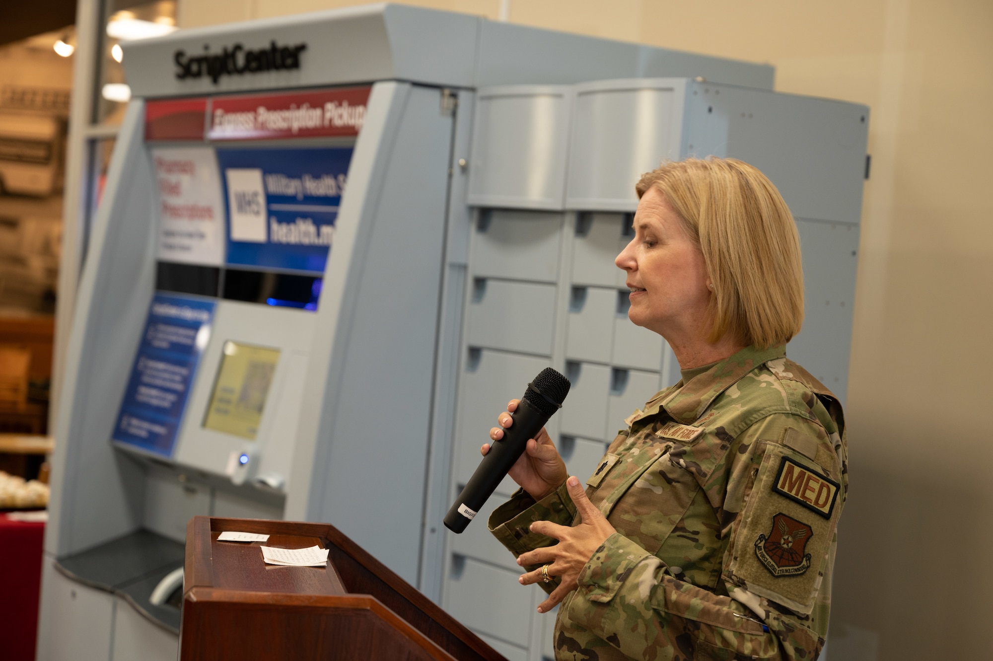 Lt. Col. Krista Hutchinson, 2nd Healthcare Operations Squadron commander, introduces the new ScriptCenter kiosk during a ribbon cutting ceremony for the pharmacy at Barksdale Air Force Base, Louisiana, Sept. 13, 2022. The kiosk provides pharmacy patients with the option to pick up eligible medications in the Base Exchange lobby during BX business hours. (U.S. Air Force photo by Senior Airman Chase Sullivan)