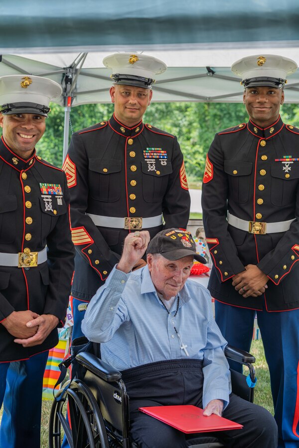 U.S. Marine Corps Veteran Pvt. Armand J. Pontbriant raises his fist with a challenge coin in hand to take a picture with U.S. Marines from Recruiting Station Boston during the celebration of his 100th birthday at the Mount Saint Rite Health Center in Cumberland, Rhode Island, Jul. 9, 2023. Armand served during World War II on the USS Rutilicus, and was a part of the Makin Island Campaign from 1943 to 1944. (Courtesy Photo)