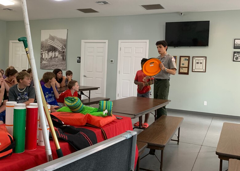 Park Ranger Giovanny Espinoza shows campers at Dale Hollow Lake Trooper Island in Burkesville, Kentucky, an example of 'THROW' from the "Reach, Throw, Row, Don’t Go" water safety method by using a rescue disk as a flotation device for a swimmer in distress.