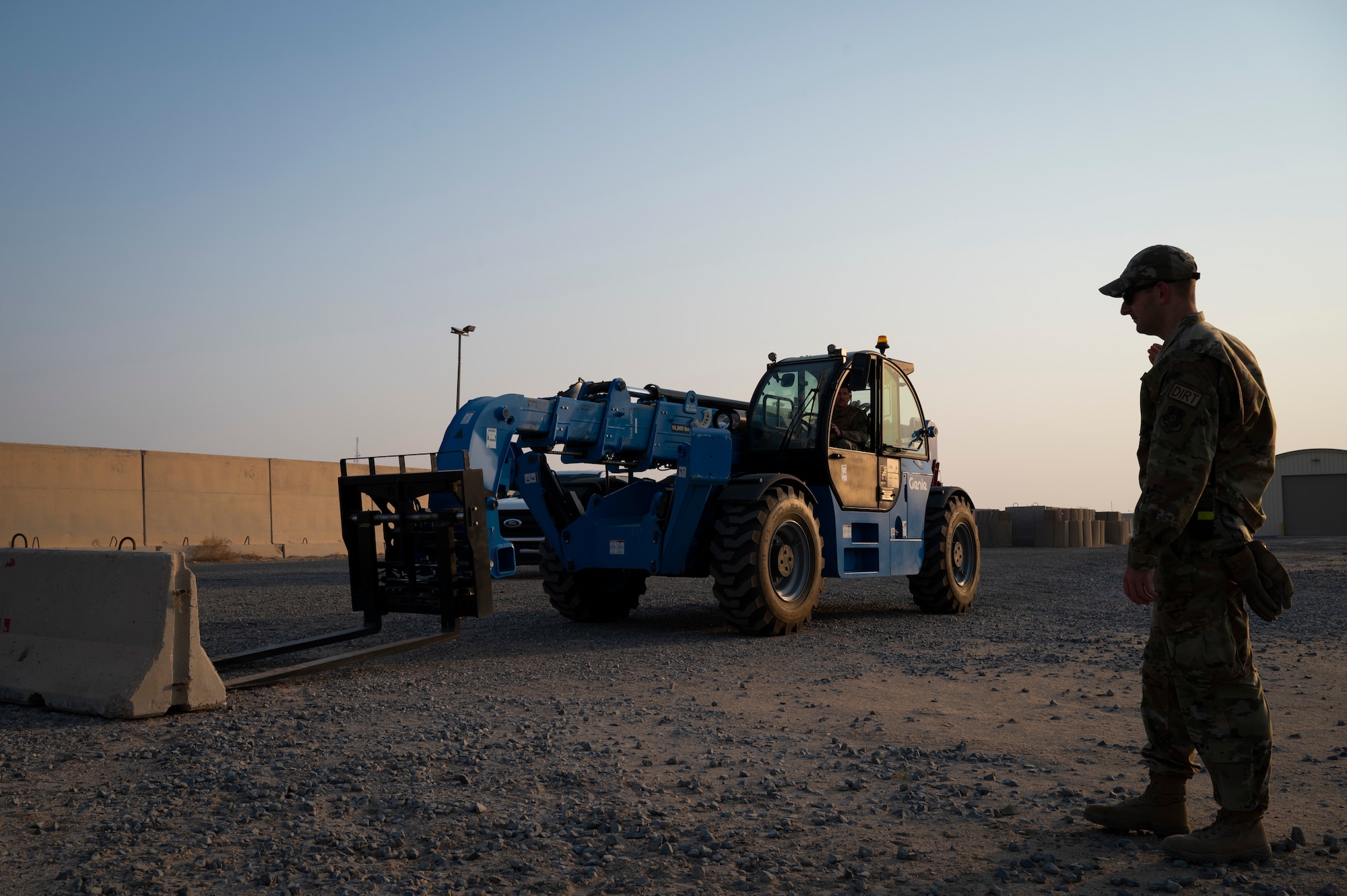 U.S. Air Force Tech. Sgt. Trenton Stone, 386th Expeditionary Civil Engineer Squadron NCOIC, guides Staff Sgt. Charles Otta, 386th Expeditionary Civil Engineer Squadron pavement and equipment supervisor, to place a security barrier down during Operation Agile Spartan III at an undisclosed location, September 10, 2022. Airmen from the 386th ECES worked to move barriers and build an additional entry control point for the 386th Expeditionary Security Forces Squadron during the exercise. (U.S. Air Force photo by Staff Sgt. Dalton Williams)