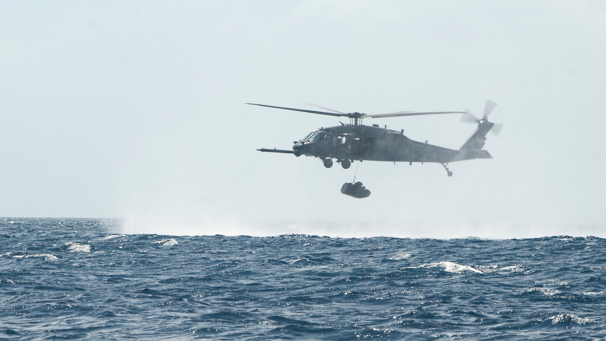 An HH-60G Pave Hawk assigned to the 33rd Rescue Squadron lowers a combat rubber raiding craft into the Pacific Ocean, September 13, 2022. The CRRC, also known as a tethered duck in this scenario, is dropped into the water and inflated by pararescuemen once they exit the aircraft. (U.S. Air Force photo by Senior Airman Jessi Roth)