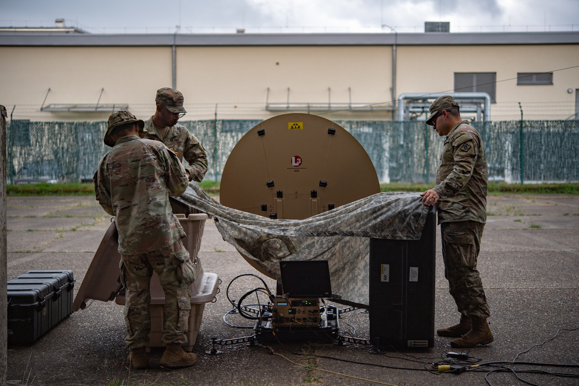 U.S. Army soldiers assigned to the 44th expeditionary signal battalion, create a shelter from the rain
