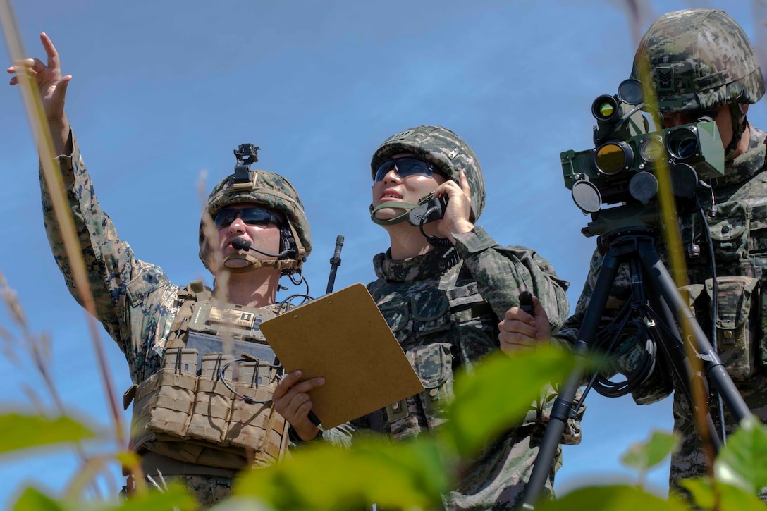 Marines point and talk on a phone during training.