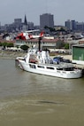 Coast Guard MH-68A HITRON  helicopter patrols over the skyline of the city of New Orleans and the cutter Dauntless as it is moored.  USCG photo by PA3 Kyle Niemi