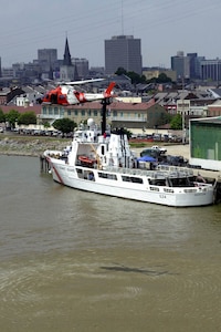 Coast Guard MH-68A HITRON  helicopter patrols over the skyline of the city of New Orleans and the cutter Dauntless as it is moored.  USCG photo by PA3 Kyle Niemi