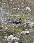 NAS Whidbey Island SAR crew members and ground rescue members move patient with broken ankle to an awaiting SAR helicopter.