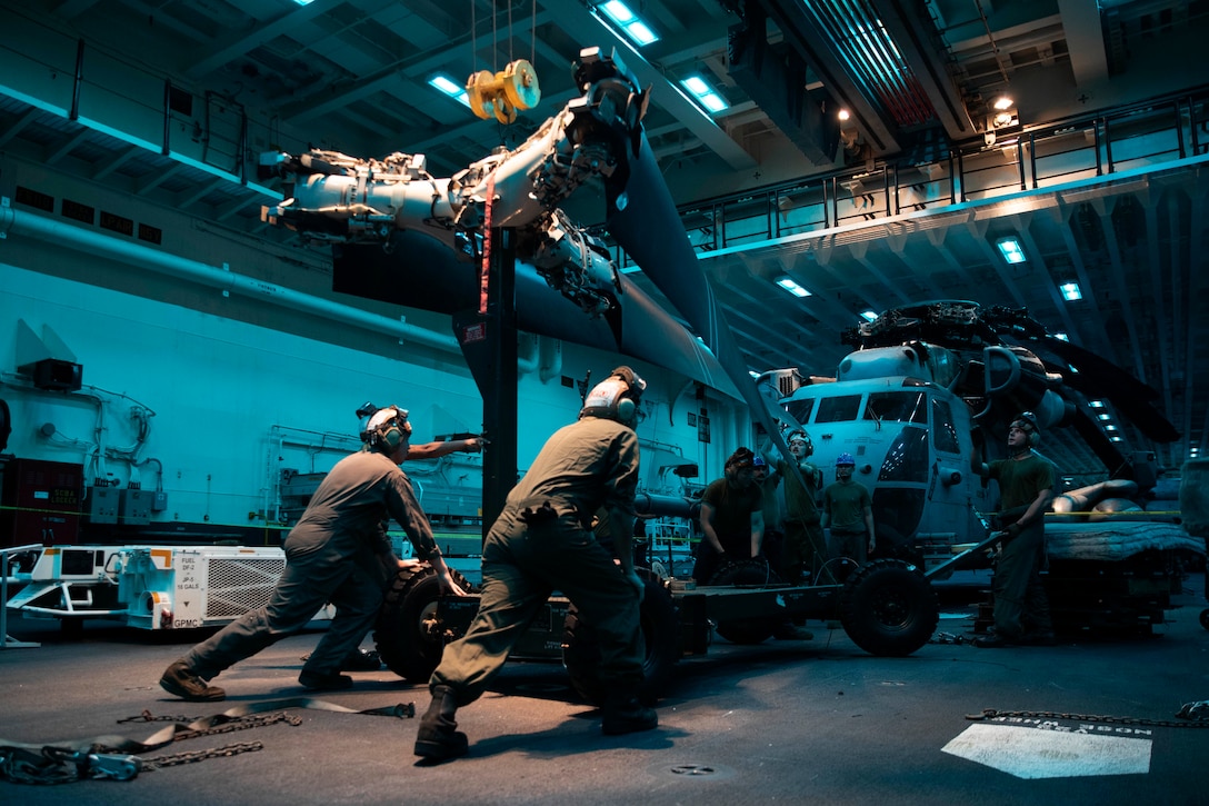U.S. Marines and U.S. Sailors conduct maintenance on the rotor assembly of an MV-22B Osprey assigned to Marine Medium Tiltrotor Squadron 262, 31st Marine Expeditionary Unit, in the hangar bay aboard amphibious assault carrier USS Tripoli Sept. 11, 2022. The 31st MEU is operating aboard ships of Amphibious Assault Ship USS Tripoli Amphibious Ready Group in the 7th Fleet area of operations to enhance interoperability with allies and partners and serve as a ready response force to defend peace and stability in the Indo-Pacific region.