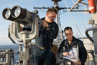Sailors aboard USS Normandy (CG 60) examine semaphore flag  signals from USNS John Lenthall (T-AO 189) during a replenishment-at-sea in the Atlantic Ocean.