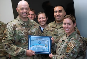 A group of people in U.S. Air Force uniforms holding an award.