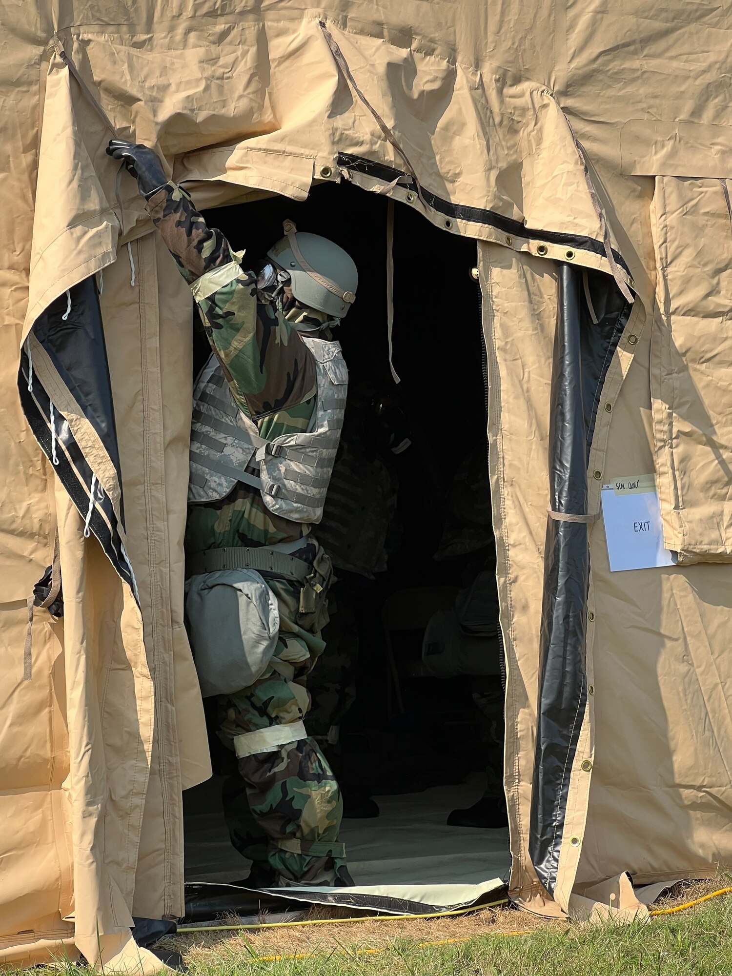An Airman ties back a doorway on a tent during a readiness exercise on Friday, September 16, 2022 at Biddle Air National Guard Base. The Airman was responding to a simulated chemical attack while trying to maintain operations in a deployed scenario.