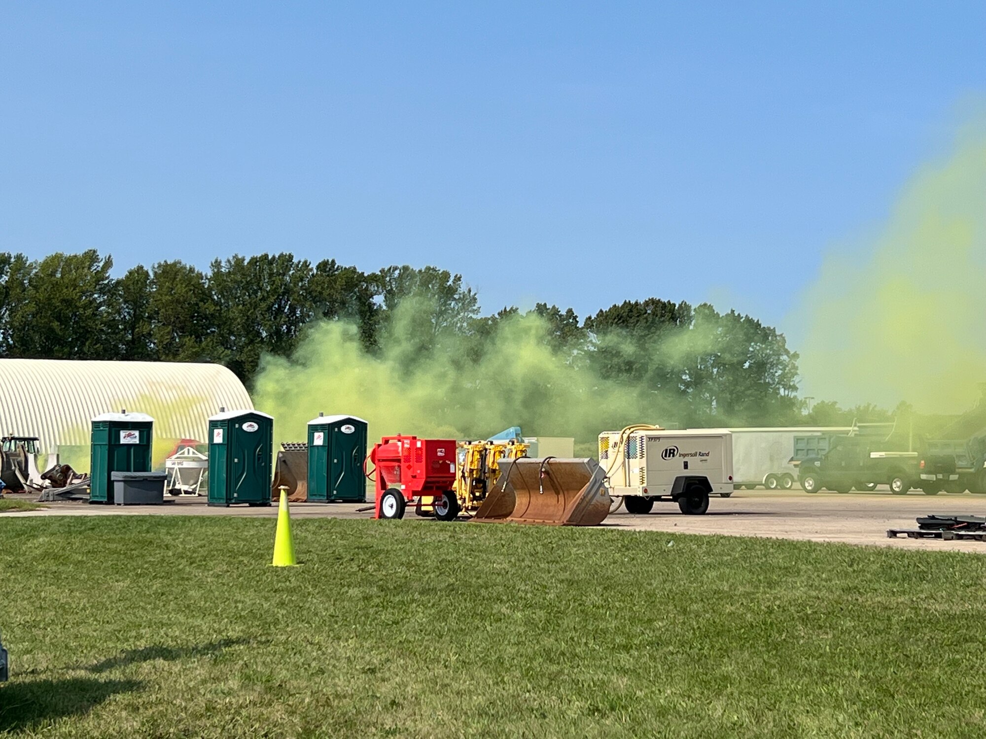 Green smoke billows near trailers equipment and portable bathrooms.