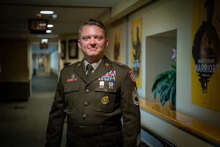 a woman wearing a u.s. army uniform stands in a hallway