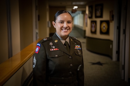 a woman wearing a u.s. army uniform stands in a hallway